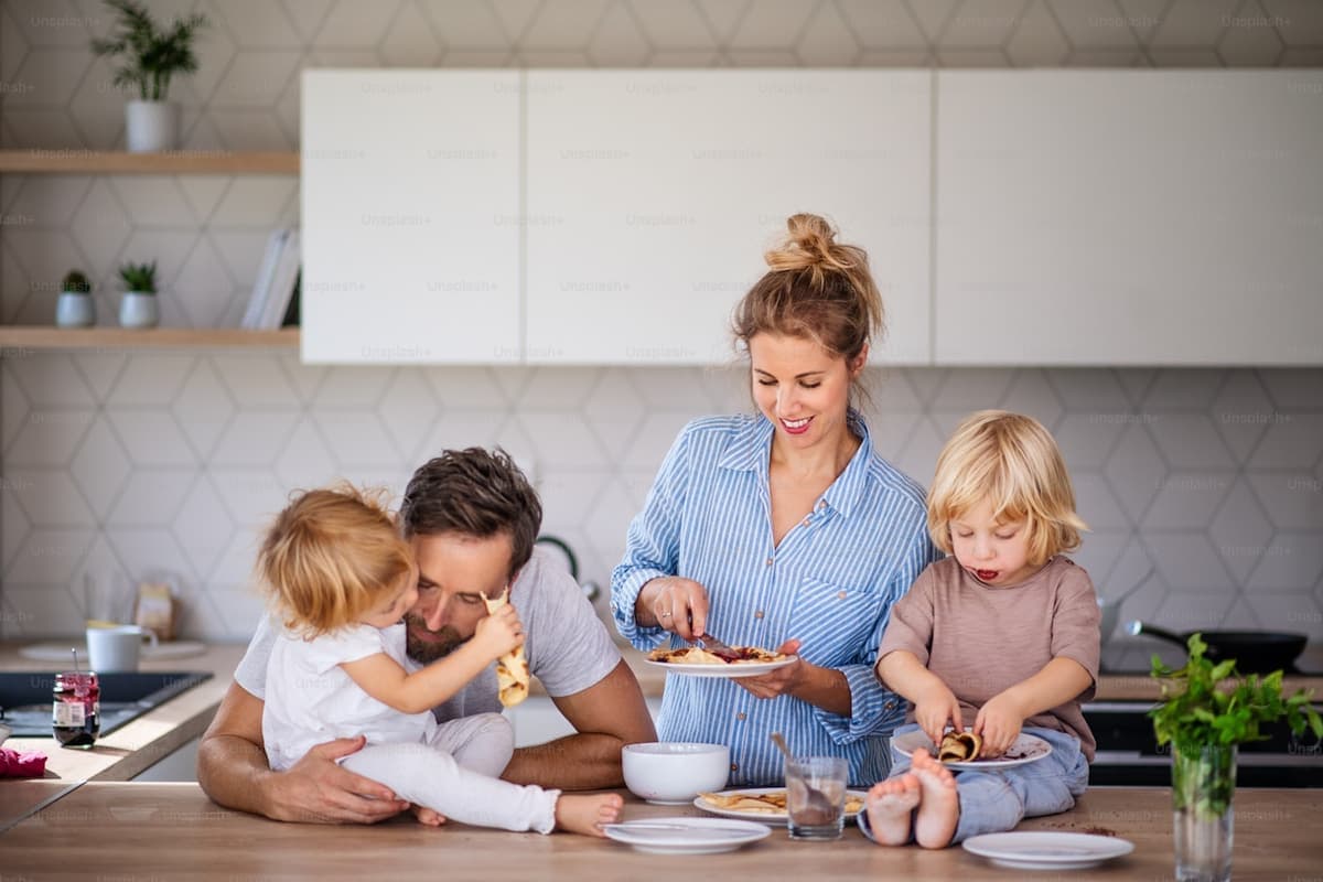 A young family making breakfast together in their kitchen, kids helping